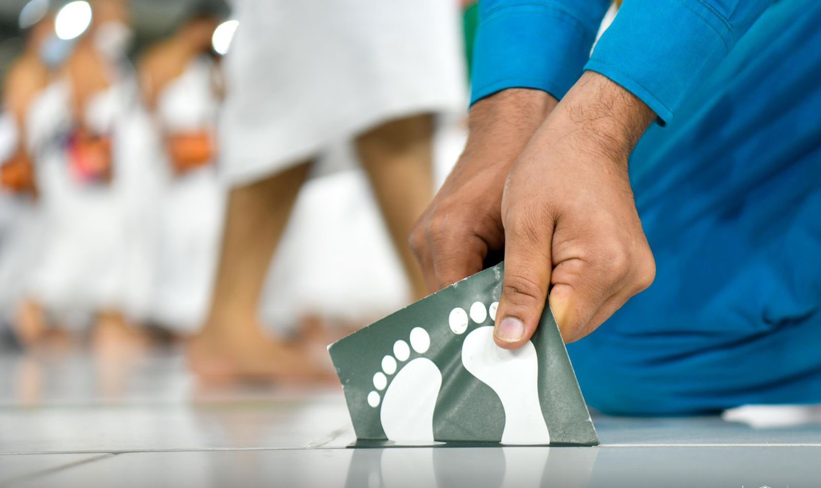 Removing “Social distancing stickers” from the Great Mosque of Mecca..